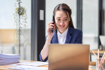 Shot of a asian young business Female working on laptop computer in her workstation.Portrait of Business people employee freelance online marketing Call phone e-commerce telemarketing concept.