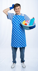 a male housewife in a blue apron rubber gloves an orange t-shirt, jeans and white sneakers holds a...