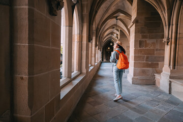 A girl traveler and tourist walks in the hall of an ancient monastery or the courtyard of the cathedral - obrazy, fototapety, plakaty