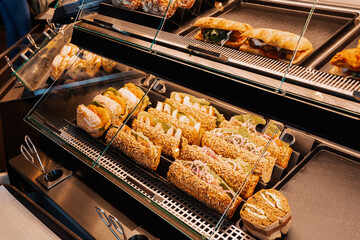 An assortment of sandwiches with various fillings are sold in the window of a store or supermarket....