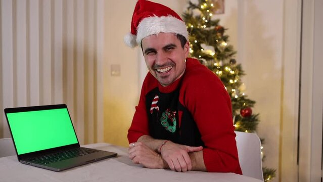 Amused festive Christmas guy watching green screen laptop laughing at funny video online, promotional material