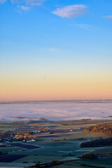 Panorama-Ausblick vom Aussichtsturm auf der Berggipfel Zabelstein bei Hundelshausen im Steigerwald, Blick über das Maintal nach Schweinfurt und Gerolzhofen bei Sonnenaufgang und Nebelschwaden