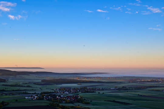 Panorama-Ausblick vom Aussichtsturm auf der Berggipfel Zabelstein bei Hundelshausen im Steigerwald, Blick &uuml;ber das Maintal nach Schweinfurt und Gerolzhofen bei Sonnenaufgang und Nebelschwaden, Deutsch