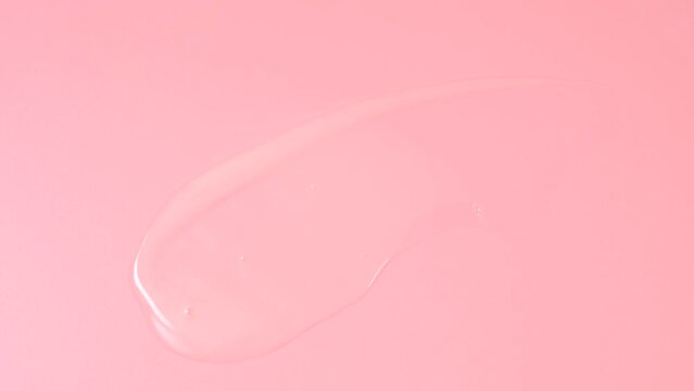 Smear of moisturizer on pink background close-up.