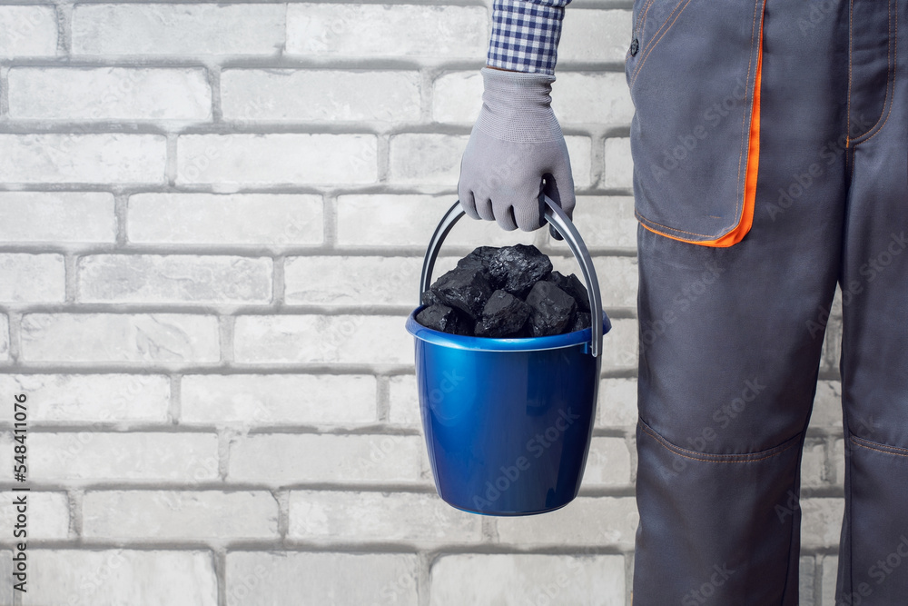 Wall mural man with backet of coal on wall brick background.