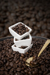 coffee beans stacked in three white dishes with a gold tea spoon