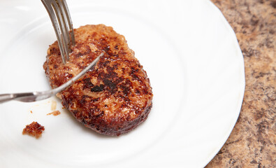 Fried cutlet with forks on a white plate.