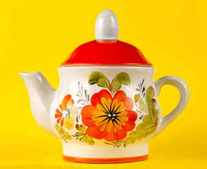 Porcelain teapot with floral ornament on a yellow background. Ceramic kettle close-up.