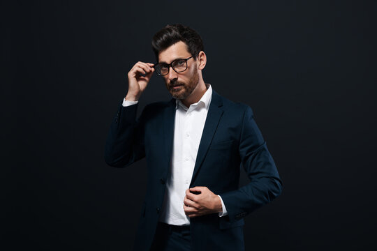Handsome bearded man with glasses on black background
