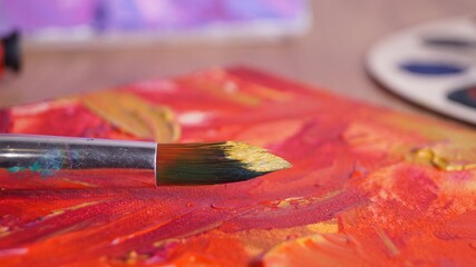 Fototapeta premium Artist's canvas with mixed paints and brush on table, closeup