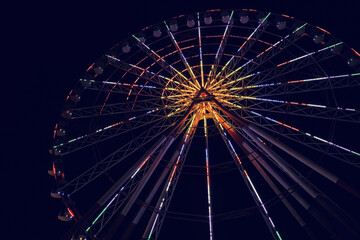 Beautiful glowing Ferris wheel against dark sky, low angle view