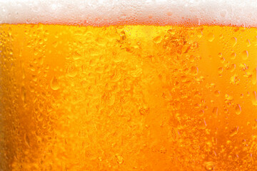 Glass of tasty cold beer with foam and condensation drops as background, closeup