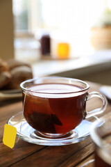 Tea bag in glass cup on wooden table indoors, closeup