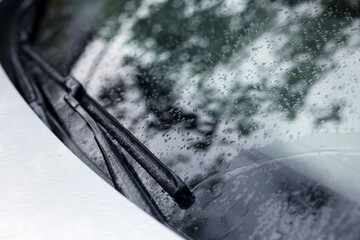 Wipers cleaning raindrops from car windshield outdoors - obrazy, fototapety, plakaty