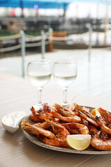 Plate of delicious cooked shrimps served with lemon and wine at table outdoors