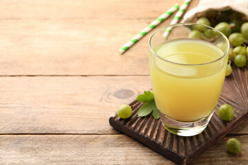 Tasty gooseberry juice and fresh berries on wooden table. Space for text