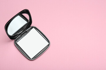 Stylish cosmetic pocket mirror on pink background, top view. Space for text