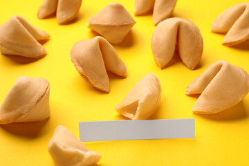 Many tasty fortune cookies with predictions on yellow background, closeup. Space for text
