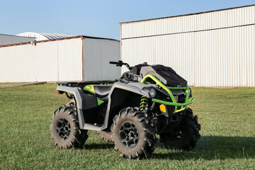Obraz premium Modern quad bike in field near hangars on sunny day