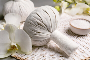 Fototapeta na wymiar Herbal massage bags and flowers on grey table, closeup. Spa supply