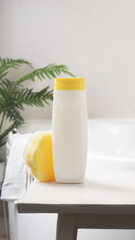 Bottle with foam bath and sponge on small table in bathroom