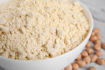 Chickpea flour in bowl and seeds on table, closeup