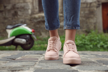 Woman in stylish sneakers walking on city street, closeup