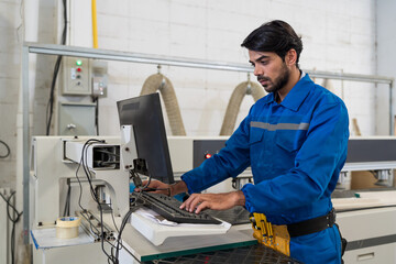 Male worker working with desk top computer for control CNC machine at workshop. Male engineer worker in safety uniform checking or maintenance computer in the industry factory. Industry manufacturing