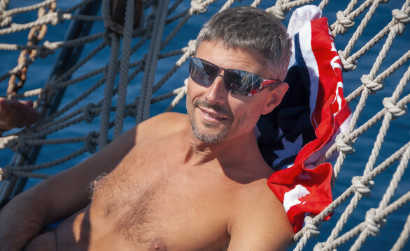 Portrait of a happy caucasian man relaxing on a cruise ship net on the bow of the ship