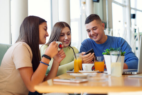 Teenagers sitting in a cafe using their mobile phones