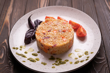 Fried rice with vegetables. Prepared and served in a plate. Natural wood background. Front view.