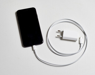 Black smartphone and white charger with cable concept energy and battery charge