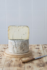 Naklejka premium Two halves of round blue cheese wheel on wooden cutting board on light background, selective focus