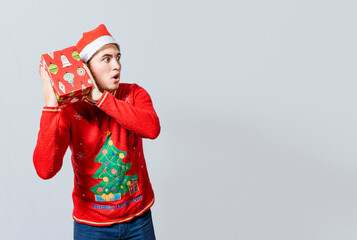 Christmas guy holding and listening a gift box. Excited christmas people holding and listening a gift. Concept of guessing a christmas gift, Christmas man holding and listening a gift box