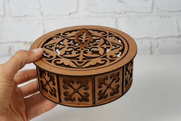 Brown carved wooden box in the hands on a light background