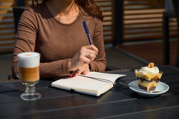 Fototapeta na wymiar A girl in a cafe writes in a notebook