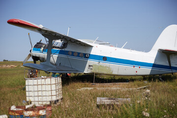 An An-2 plane is on the ground, an old plane in the neighborhood lies all sorts of junk