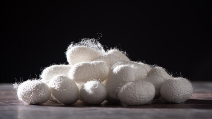 natural silk with silkworm cocoons on table. - obrazy, fototapety, plakaty