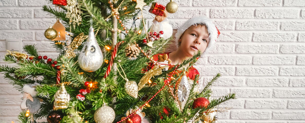 Little child with decorated Christmas tree, copy space.