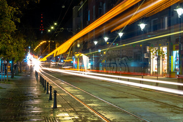 Fototapeta na wymiar Night scene of tram in traffic at crossing with lighttrail motion blur