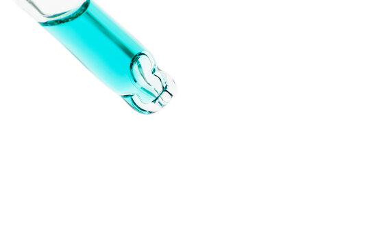 close up macro of pipette dropper with blue liquid serum on a white background