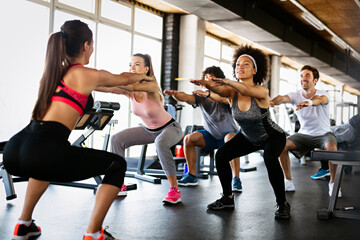 Multiethnic group of people training in a gym. Trainer and sportive fit persons exercising