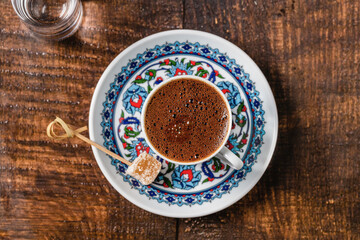 Turkish coffee in classic coffee cup with water and Turkish delight on wooden table