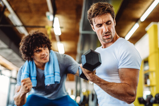Fitness, sport, exercising concept. Fit man exercising together with his personal trainer in gym.