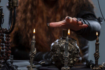 A woman's hand over a candle conducts a ceremony. Magic, the occult and rituals. Close-up. Dark...