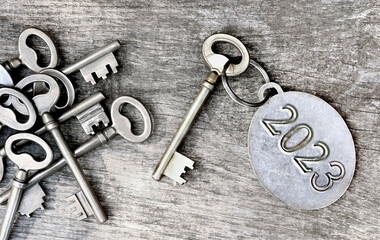  2023 engraved on a ring of an old key on wooden background