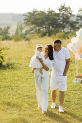 Fototapeta premium Young family with cute little daughter walking in forest on the sunset