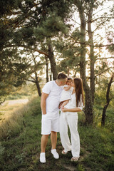 Fototapeta premium Young family with cute little daughter walking in forest on the sunset
