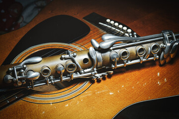 An antique clarinet resting on acoustic guitar