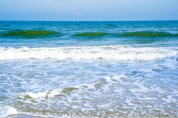 Light blue sea waves on a clean sandy beach..